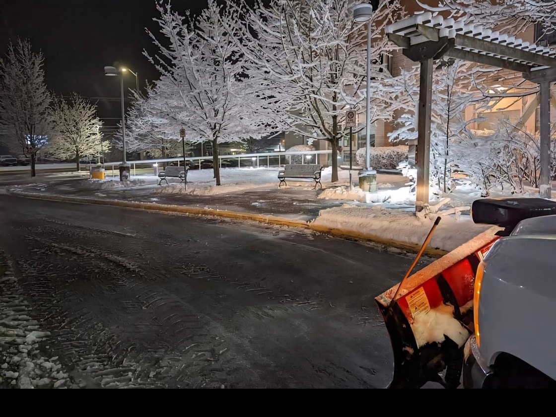A Nansan Farms plow clearing a snowy street at dusk